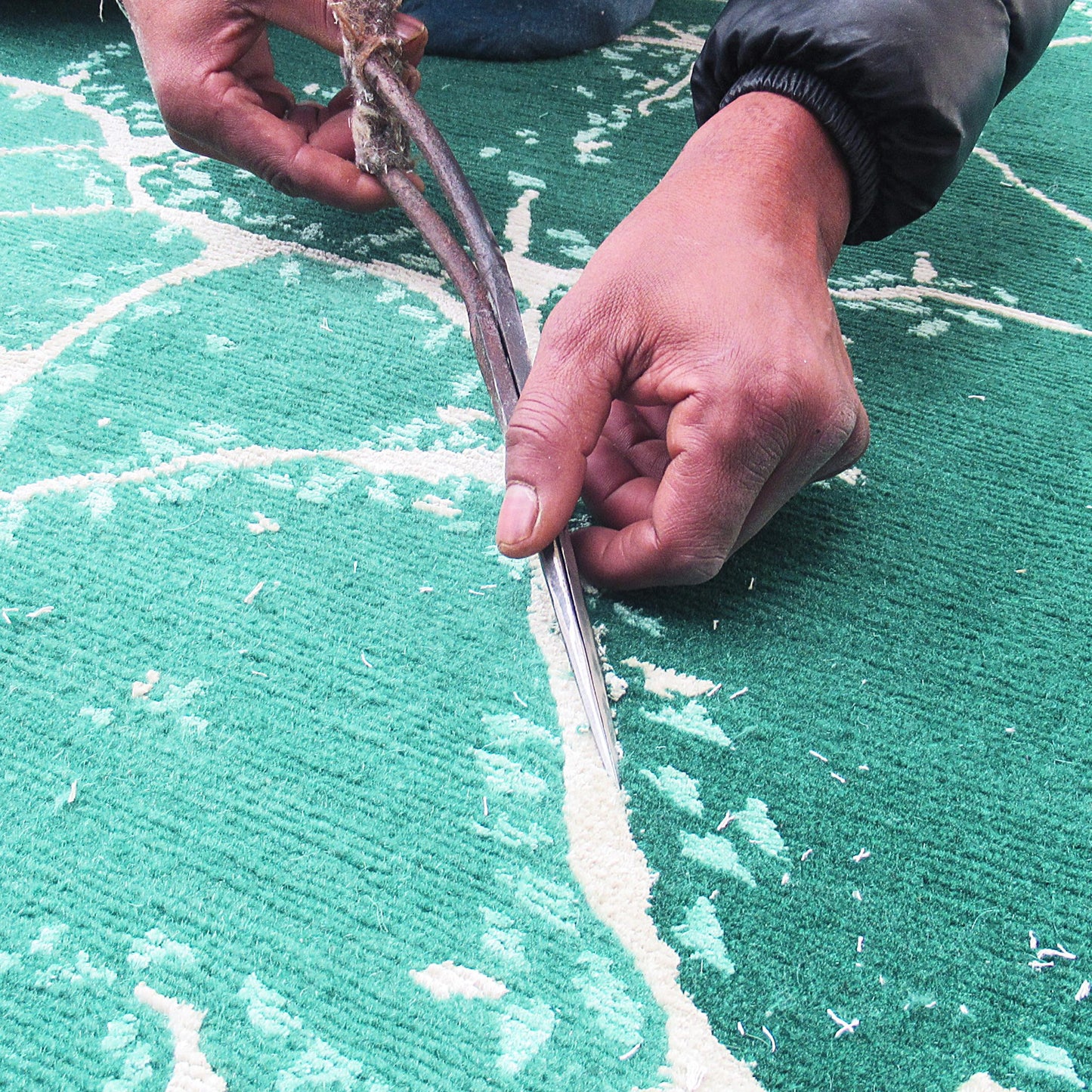 A man cutting an Aventurine Rug with scissors