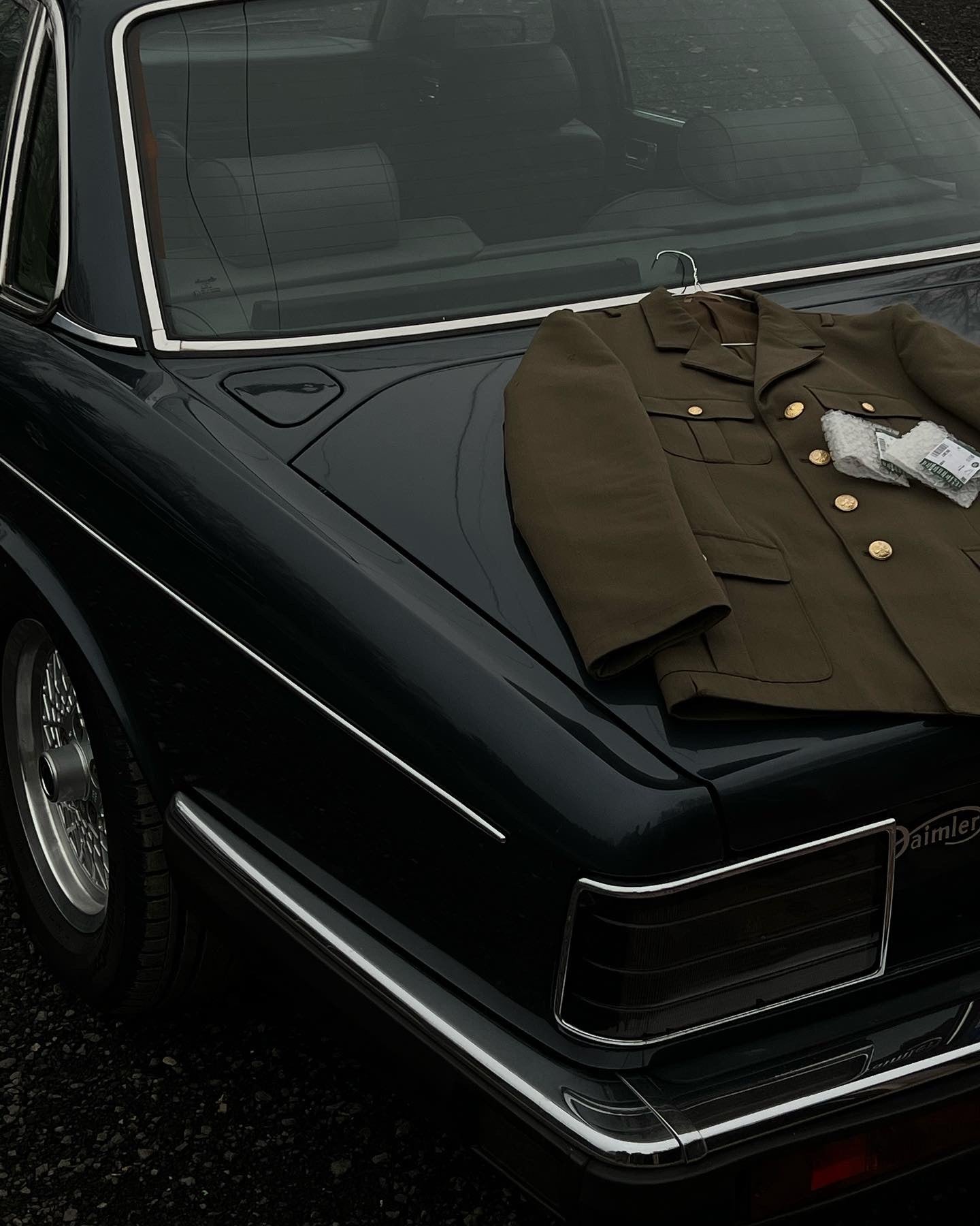 Brown army men’s coat on the trunk of a car