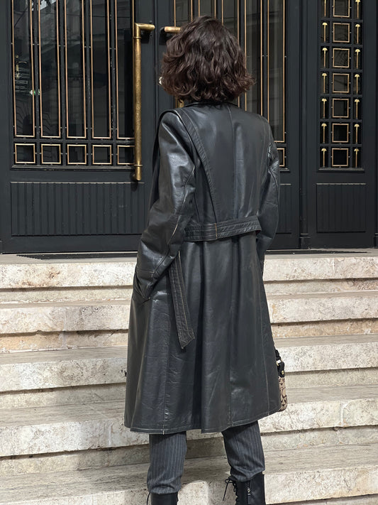 the back angle of a woman wearing a black leather trench coat