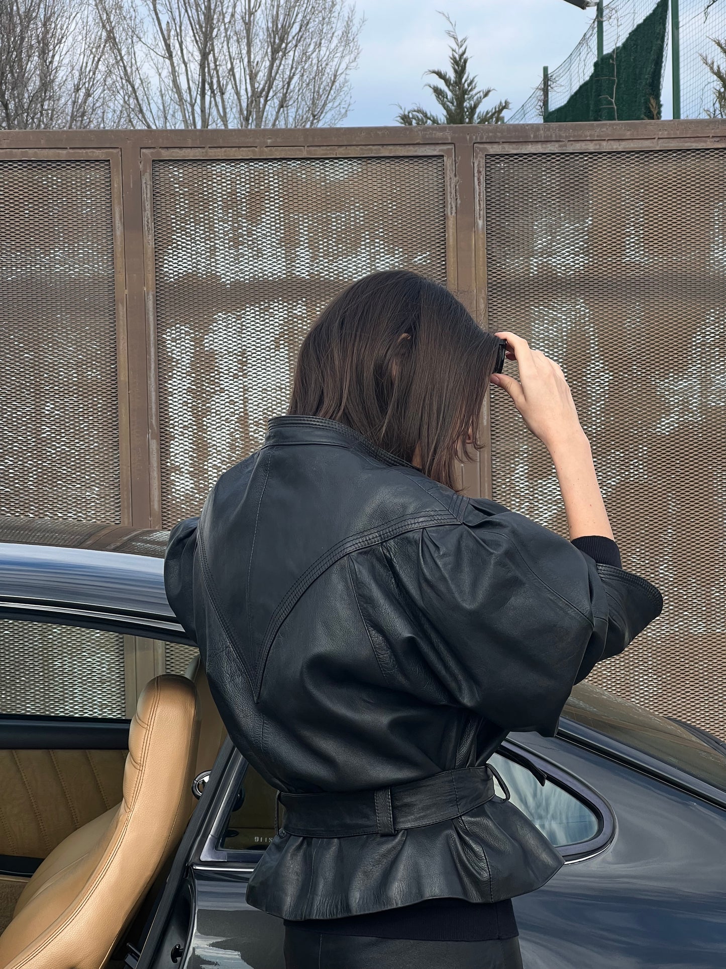 woman wearing a black woman’s leather jacket looking away