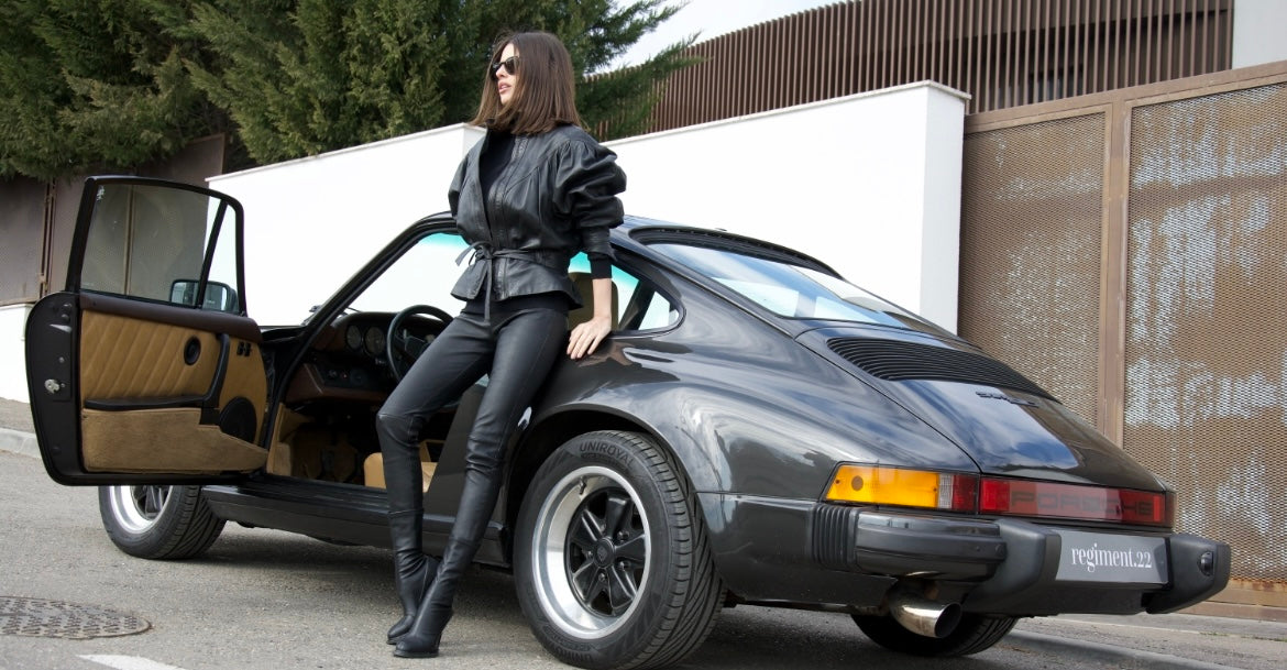 woman leaning on a car, wearing a black woman’s leather jacket